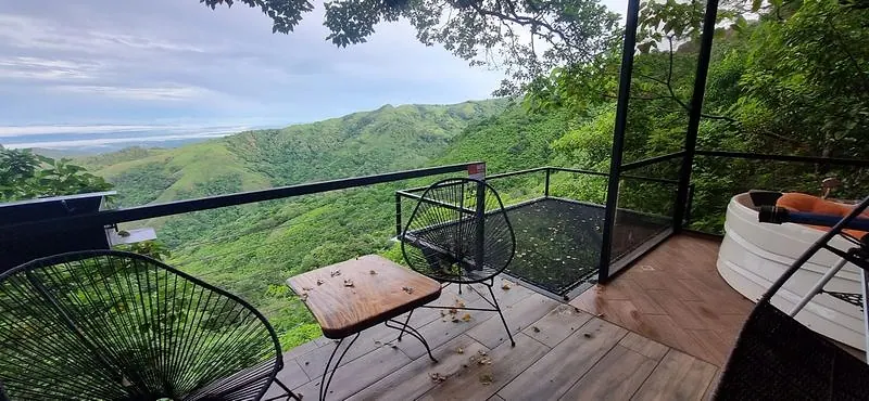 Balcón con red de descanso, mobiliario y vista abierta a la montaña