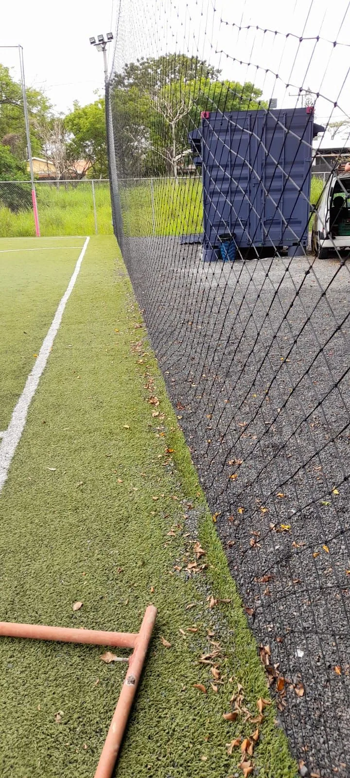 Detalle del tejido de la malla perimetral, con la cancha al fondo