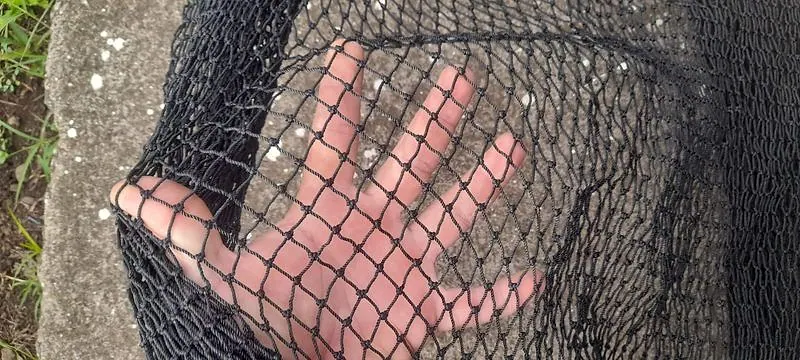 Mano detrás de la malla negra instalada: casi no se nota contra el exterior
