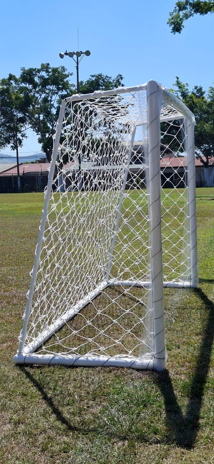 Marco de fútbol con red blanca montado sobre grama natural
