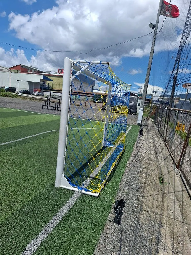 Marco de fútbol con la red instalada, visto desde la línea de banda de una cancha sintética