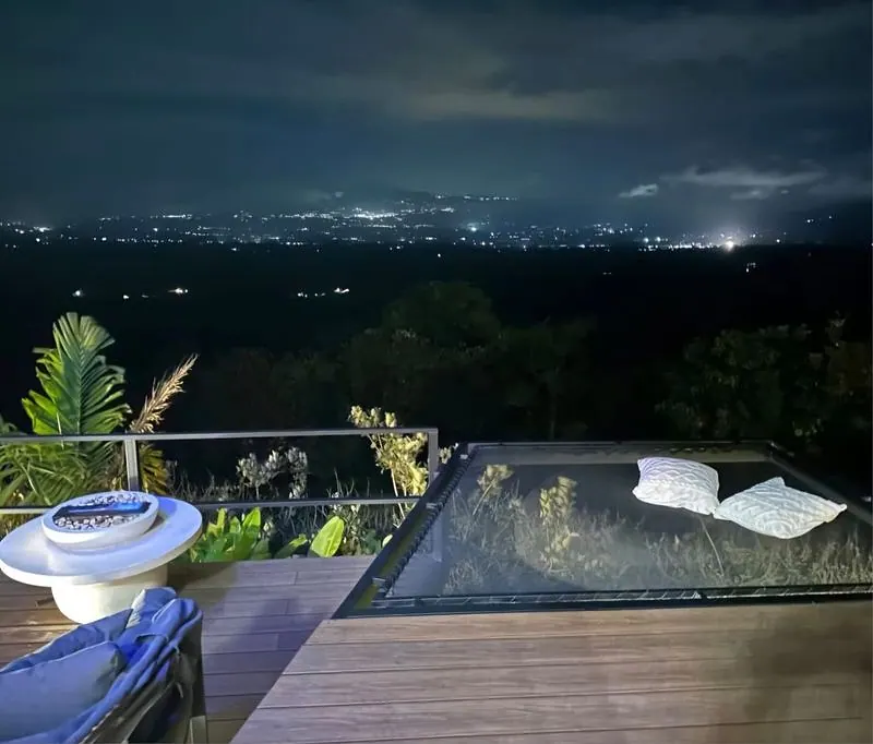 Red de descanso en una terraza de noche, con las luces del valle al fondo